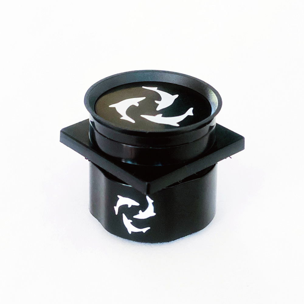 Schwarzes Kunststoff-Bauteil, runder Deckel, weiße Delfinmotive im Kreis, quadratische Basis, EAN: 0023632139184.