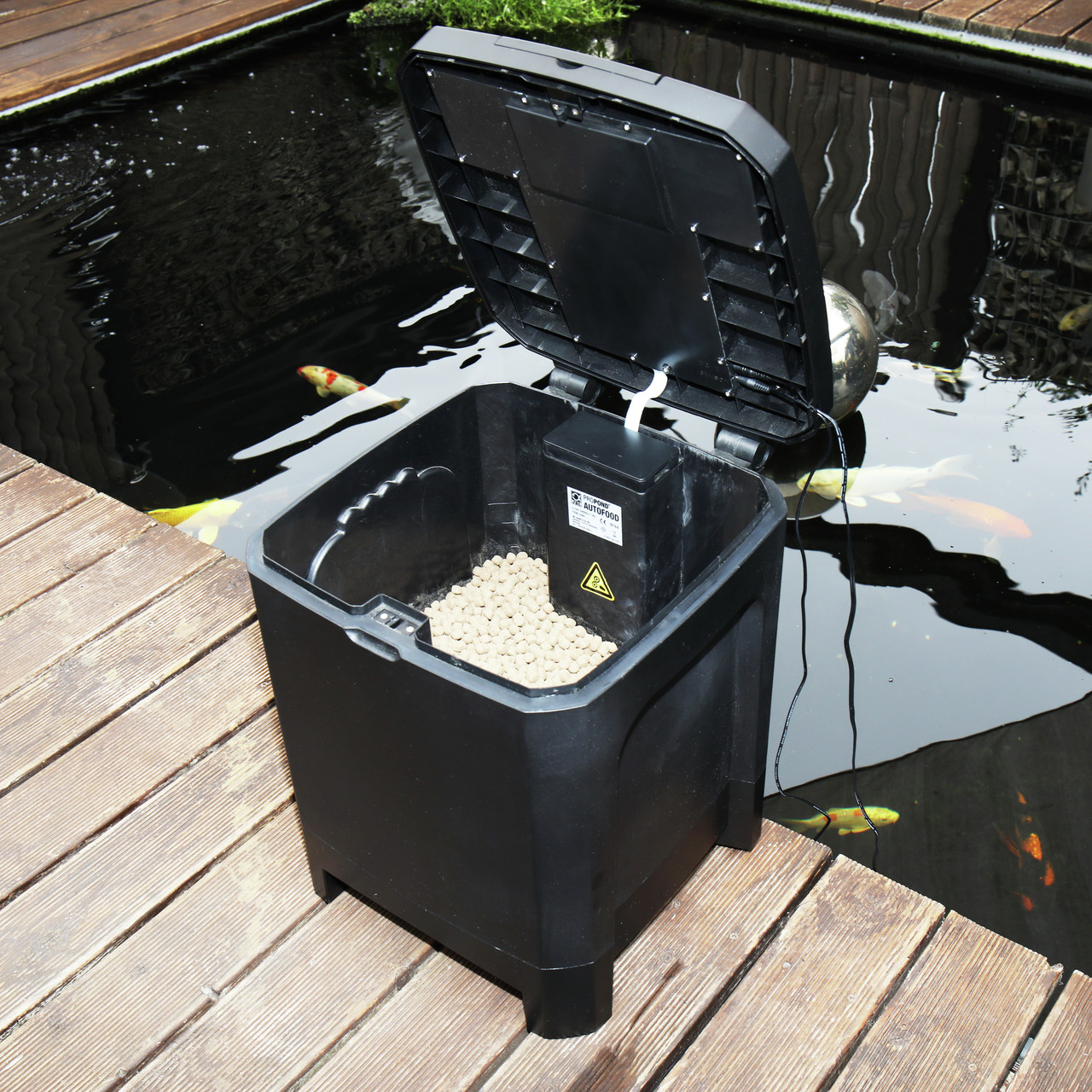 JBL AutoFood Futterspender, für Teichfische, präzise Fütterung, mit Futterpellets, ideal für Koi, schwarz, autom., auf Terrasse.