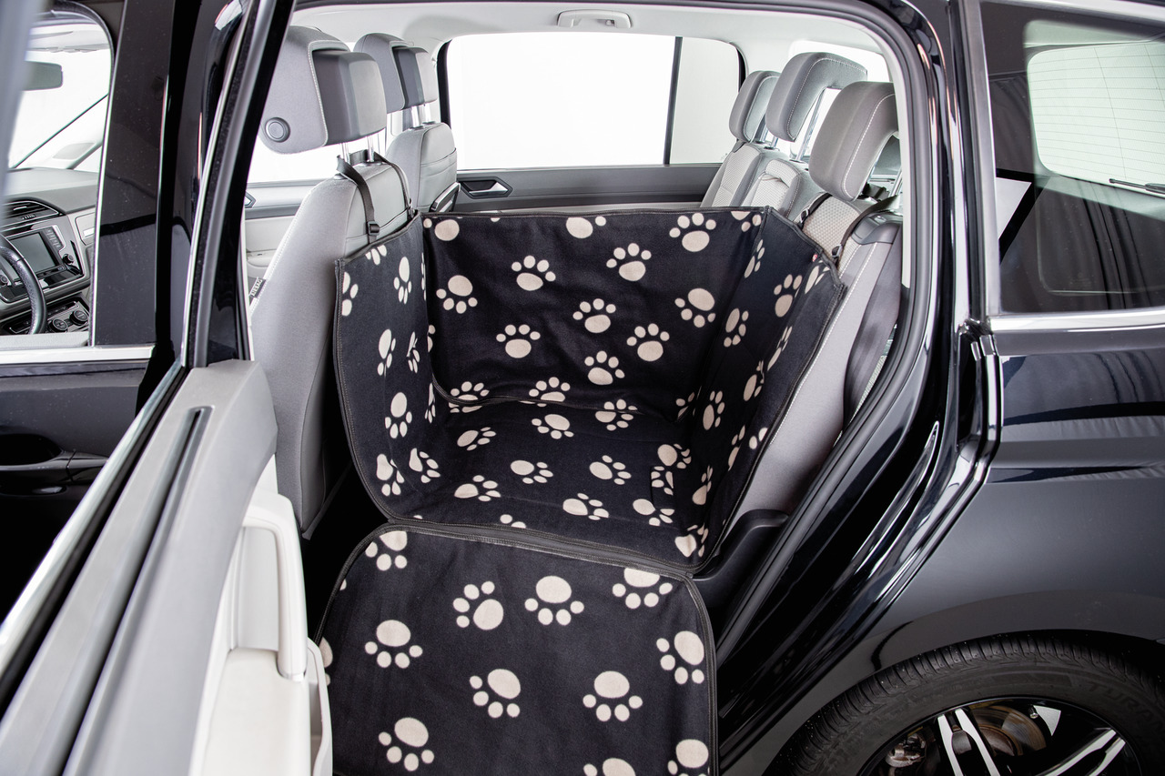 Schwarze Autoschondecke von TRIXIE mit weißen Pfotenmustern, speziell für Hunde entwickelt. Die Decke schützt die Rückbank vor Schmutz und Tierhaaren und ist ideal für den Transport von Haustieren. Sie ist leicht anzubringen und passt in die meisten Fahrz