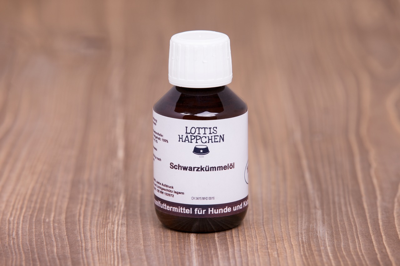 Das Bild zeigt eine braune Glasflasche mit weißem Schraubverschluss, die auf einer Holzoberfläche steht. Auf dem Etikett ist die Marke „Lottis Häppchen“ sowie der Produktname „Schwarzkümmelöl“ zu sehen. Es handelt sich um ein Ergänzungsfuttermittel für Hu