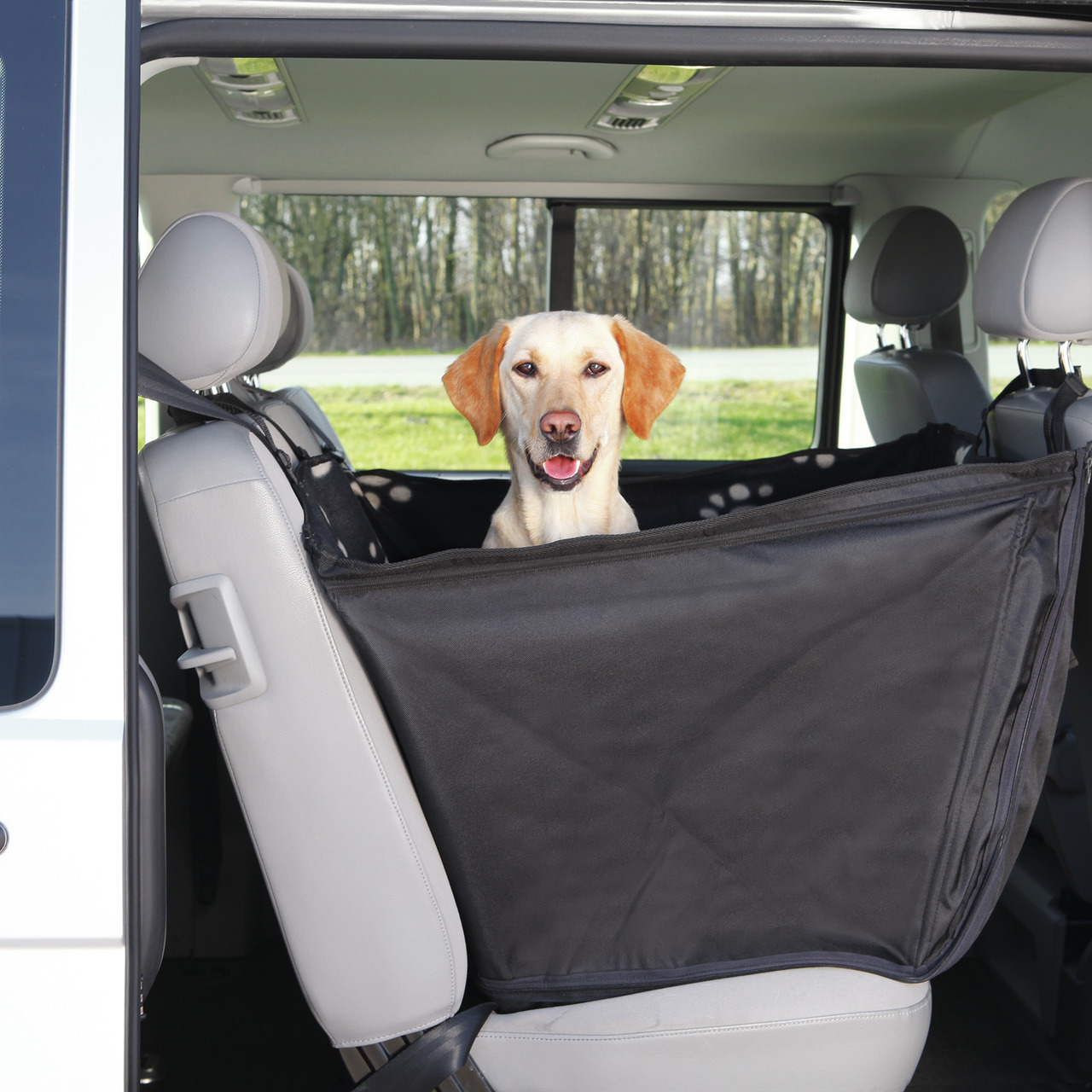 Auf dem Bild ist eine schwarze Autoschondecke der Marke TRIXIE zu sehen, die auf der Rückbank eines Fahrzeugs befestigt ist. Sie dient dem Schutz der Autositze vor Schmutz und Tierhaaren und bietet Hunden eine sichere und komfortable Transportmöglichkeit.
