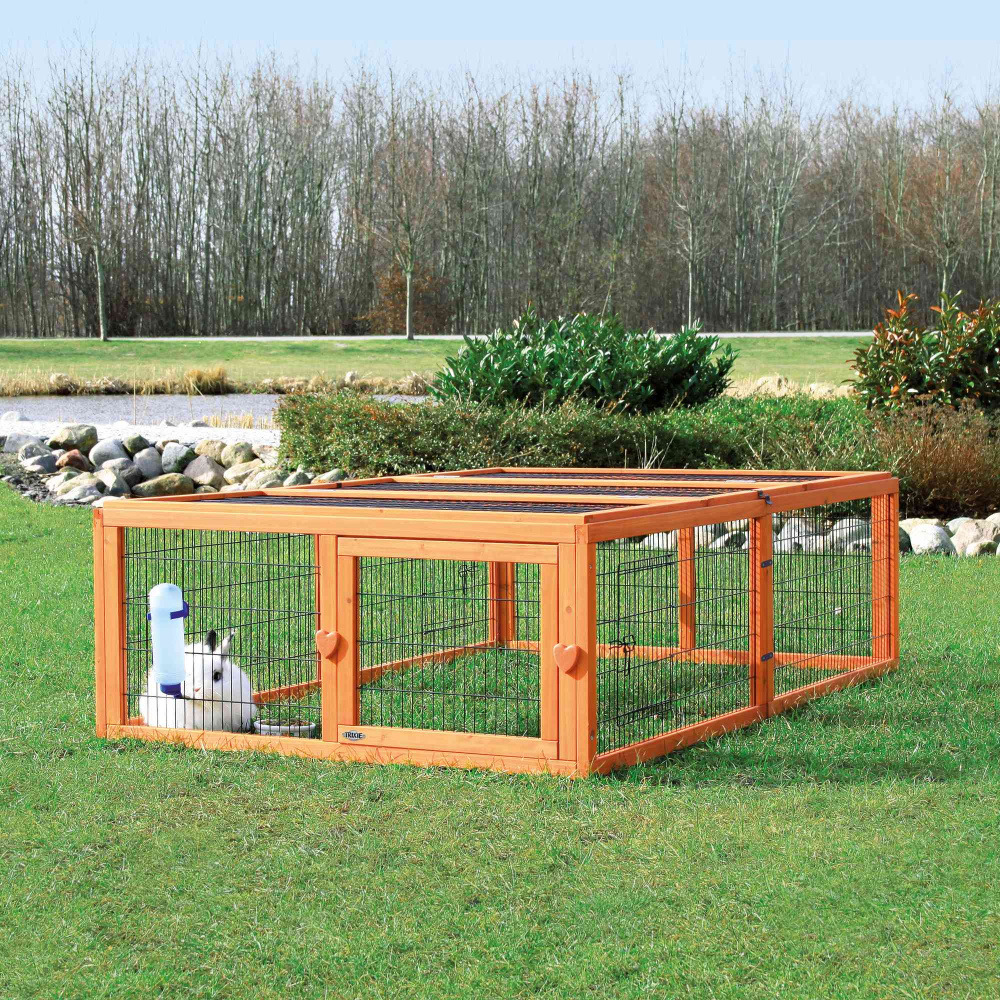 Das Bild zeigt das TRIXIE Freigehege für Kleintiere, geeignet für Kaninchen und Meerschweinchen. Es besteht aus einem stabilen Holzrahmen mit Drahtgitter und bietet eine sichere, geräumige Umgebung im Freien. Im Gehege ist ein weißes Kaninchen mit einer b
