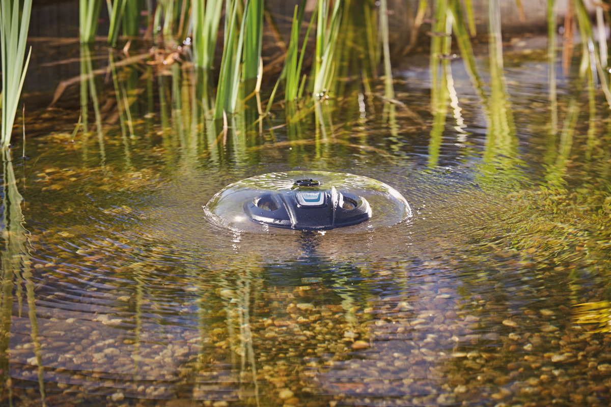 Das Bild zeigt den Oase AquaSkim 20, einen Oberflächenabsauger für Teiche, der effektiv Schmutz wie Blätter und Pollen von der Wasseroberfläche entfernt. Der schwimmende Skimmer ist in einem klaren Teich mit Pflanzen am Rand zu sehen. Ideal für Teichbesit