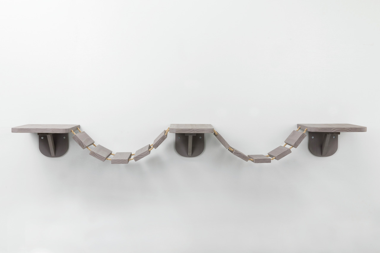 Das Bild zeigt das Produkt „TRIXIE Wandliege-Set mit Hängebrücke“ für Katzen. Es besteht aus zwei Wandliegen und einer verbindenden Hängebrücke aus Holz in Grau. Geeignet für Katzen aller Größen, bietet es eine ideale Kletter- und Ruhefläche. Perfekt für 