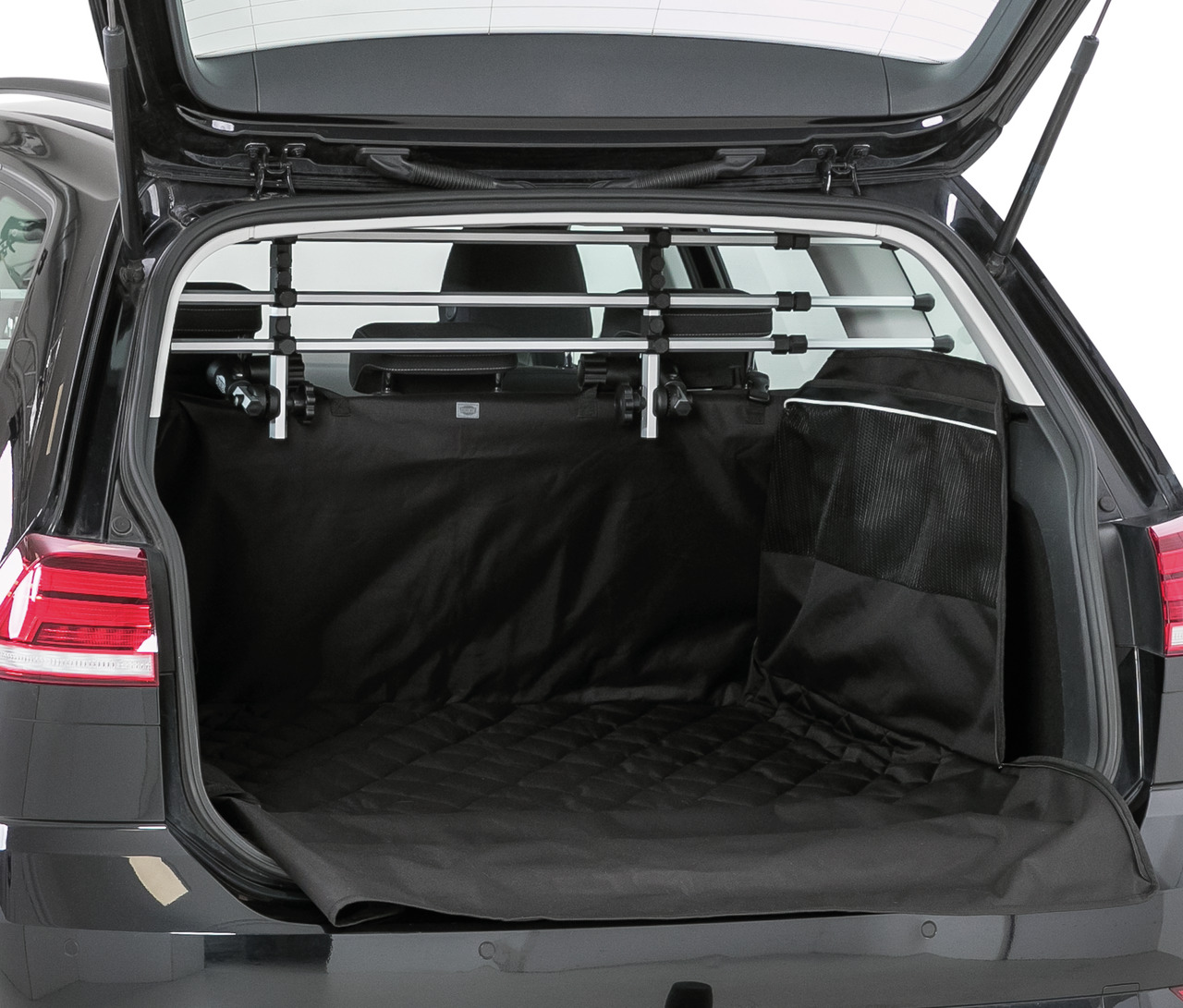 Das Bild zeigt den geöffneten Kofferraum eines Autos, ausgestattet mit dem TRIXIE Kofferraum-Schutzdecke-Set, ideal für Hundebesitzer. Die schwarze Schutzdecke schützt den Kofferraum vor Schmutz und Tierhaaren. Zusätzlich ist eine verstellbare Hundegitter