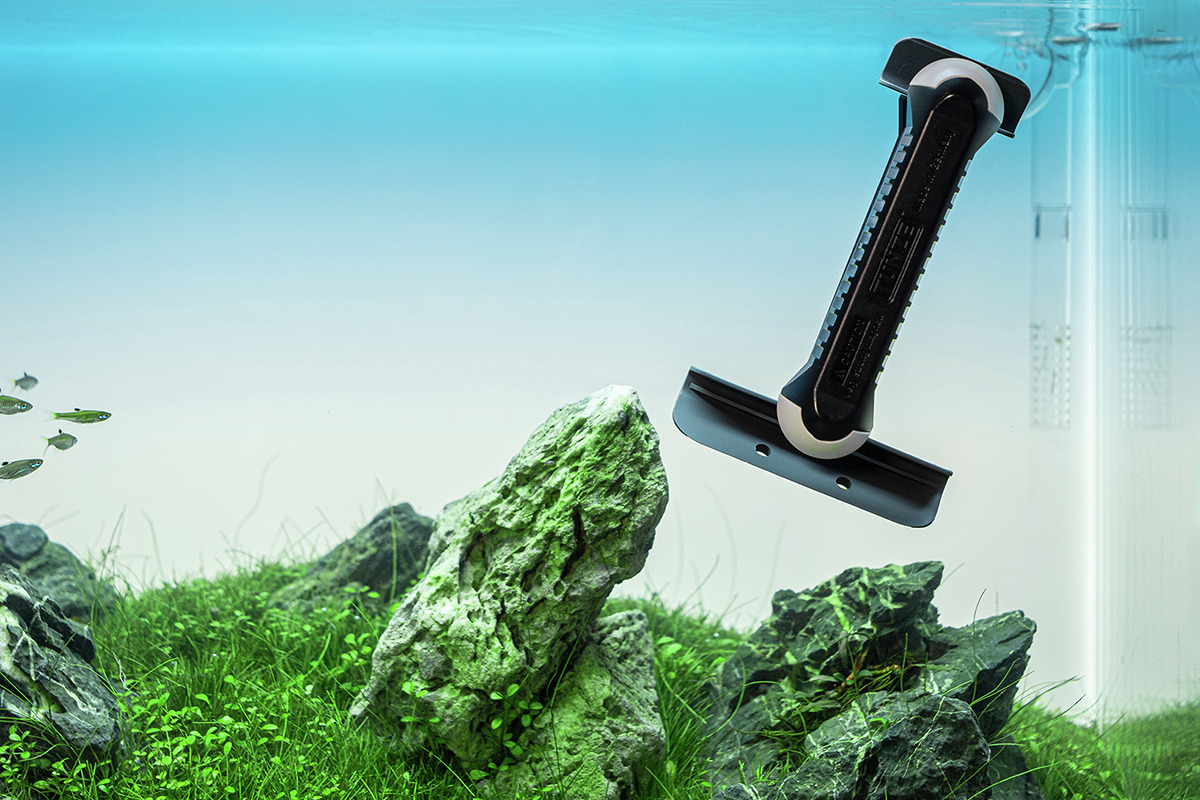 Ein TUNZE Care Magnet, ein innovativer Scheibenreiniger für Aquarien, schwebt unter Wasser in einem bepflanzten Aquarium. Der Reiniger ist ergonomisch geformt und eignet sich für die gründliche Reinigung von Aquarienscheiben, ohne Kratzer zu hinterlassen.