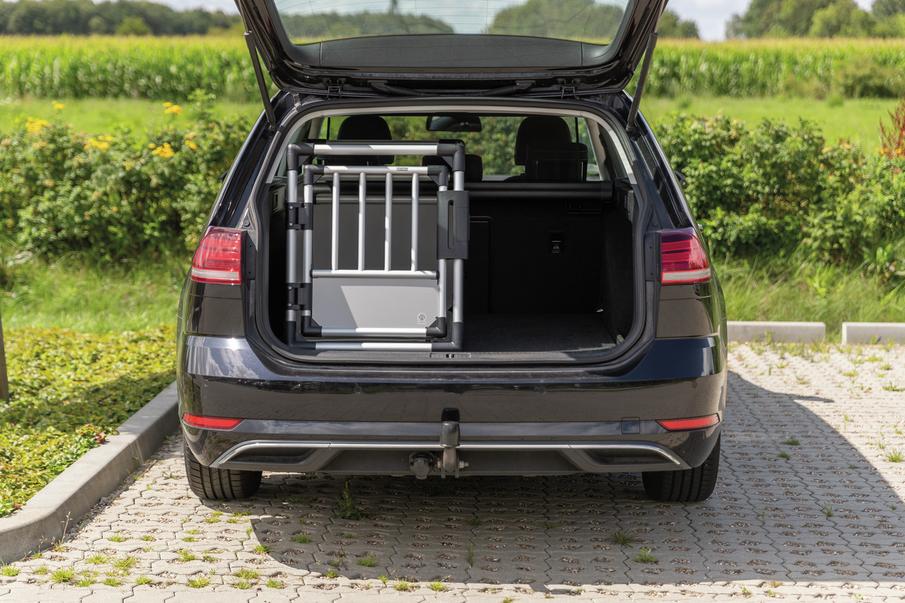 Das Bild zeigt einen geöffneten Kofferraum eines schwarzen Kombis, in dem eine silberne Hundetransportbox der Marke TRIXIE zu sehen ist. Die Box ist robust und aus Aluminium gefertigt, ideal für den sicheren Transport von Hunden. Sie richtet sich an Hunde