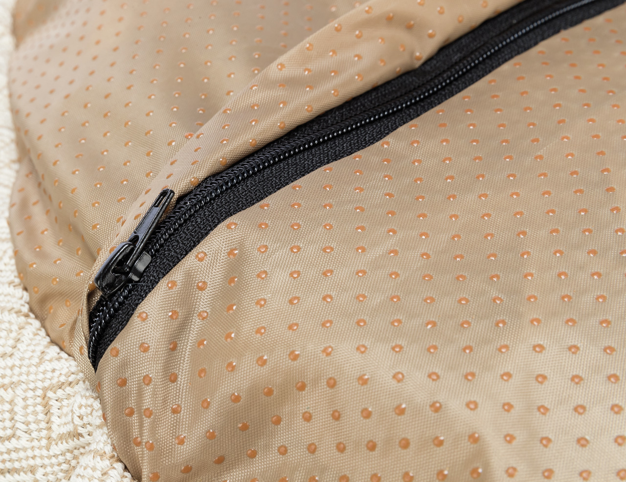 Das Bild zeigt ein Detail des TRIXIE Hundeschlafsacks, der speziell für Hunde entwickelt wurde. Der Schlafsack besteht aus einem beige-braunen, rutschfesten Material mit kleinen Noppen und einem schwarzen Reißverschluss. Er bietet Komfort und Wärme für Hu
