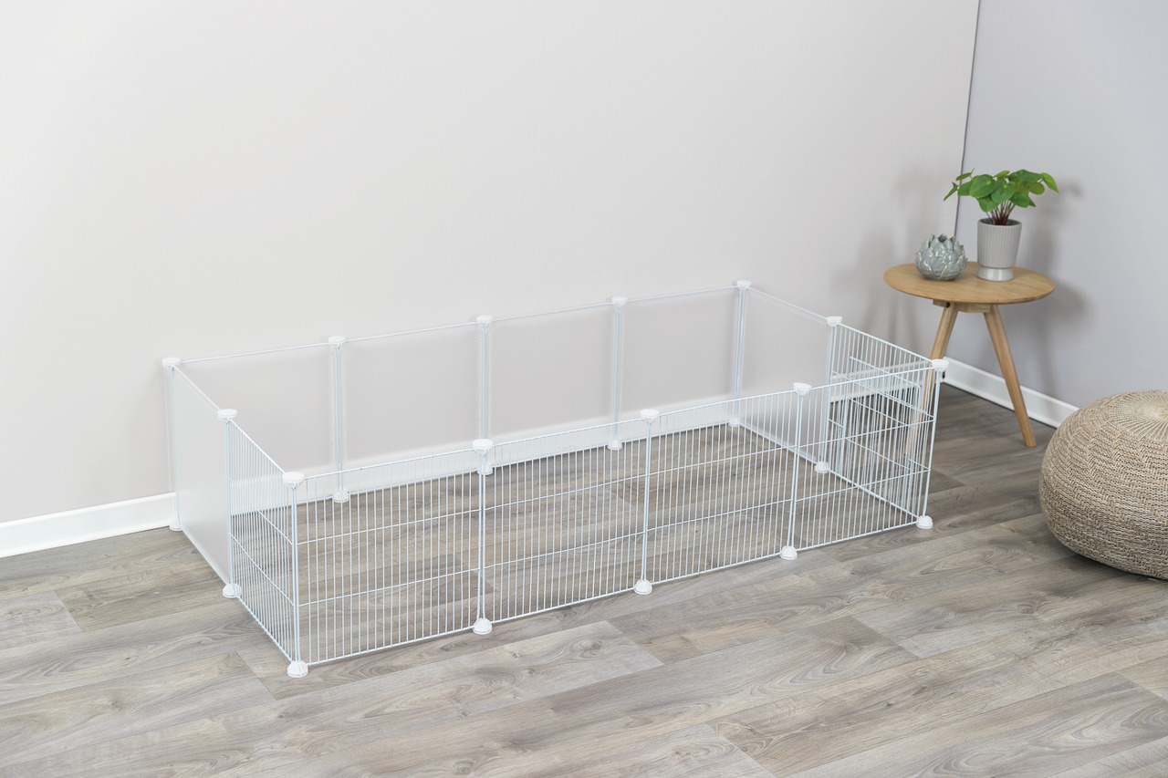 Das Bild zeigt den TRIXIE Freilaufgehege für Kleintiere, geeignet für Kaninchen und Meerschweinchen. Das Gehege besteht aus weißen Gitterelementen und transparenten Kunststoffwänden, die eine sichere Umgebung bieten. Es ist modular aufgebaut und kann indi