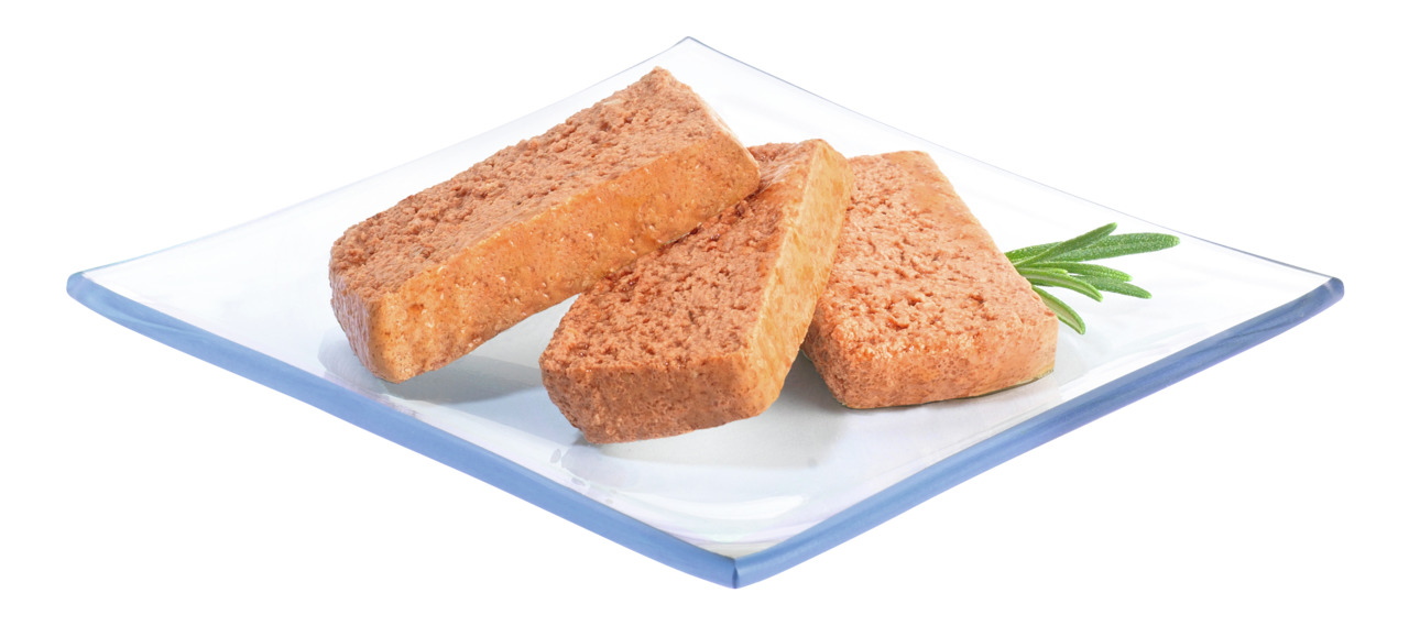Auf dem Bild sind drei rechteckige, fleischähnliche Snacks der Marke PREMIERE zu sehen, die auf einem weißen Teller mit einem Rosmarinzweig angerichtet sind. Es handelt sich um ein Produkt für Hunde, vermutlich mit Fleischgeschmack. Die EAN 4047777087564 