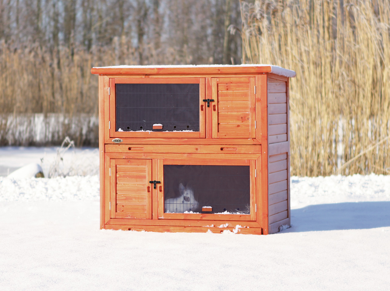 Das Bild zeigt den TRIXIE Natura Kleintierstall, ein hochwertiges Produkt für Kleintiere wie Kaninchen oder Meerschweinchen. Der Stall besteht aus wetterfestem Holz in warmem Braunton und ist für den Außenbereich geeignet. Er verfügt über zwei Ebenen mit 