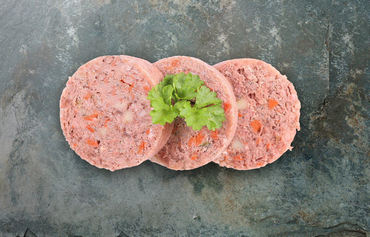 Das Bild zeigt drei Scheiben des Hundefutters „Lakefields Nassfutter Rind mit Karotte & Kartoffel“ auf einer dunklen Steinplatte, dekoriert mit einem frischen Petersilienblatt. Das Futter ist für Hunde geeignet, enthält Rindfleisch, Karotten und Kartoffel