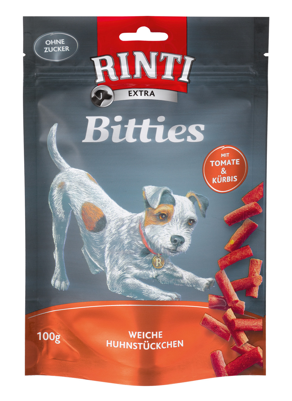 Die Verpackung zeigt das Produkt "RINTI Extra Bitties" für Hunde. Es handelt sich um weiche Huhnstückchen mit Tomate und Kürbis, geeignet als Snack für Hunde. Die Packung enthält 100 g und ist ohne Zuckerzusatz. Auf der Vorderseite ist ein Hund abgebildet