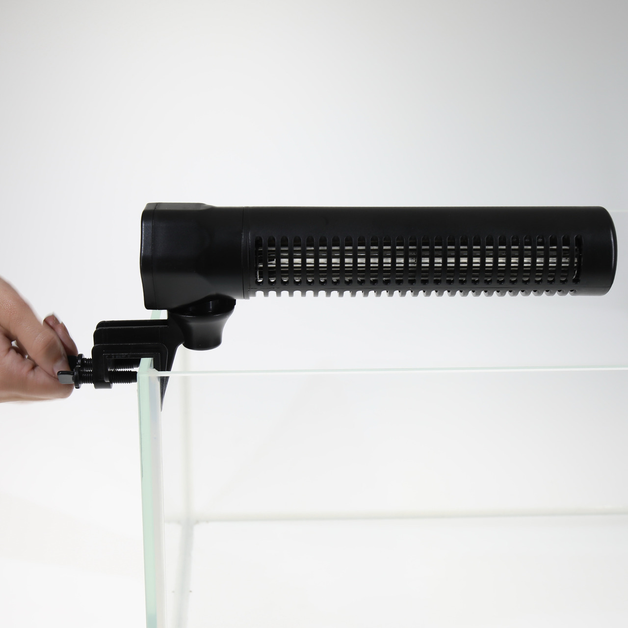 Das Bild zeigt den JBL ProTemp S300, einen schwarzen, stabförmigen Aquarienheizer, der an der Glaswand eines Aquariums befestigt wird. Eine Hand justiert die Halterung, um den Heizer sicher zu fixieren. Der Heizer ist für Aquarienbesitzer geeignet und sor