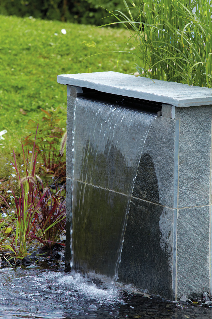 Oase Wasserspiel, rechteckiger grauer Steinbrunnen mit sanftem Wasserfall, ideal für Garten, schafft natürliche Atmosphäre.