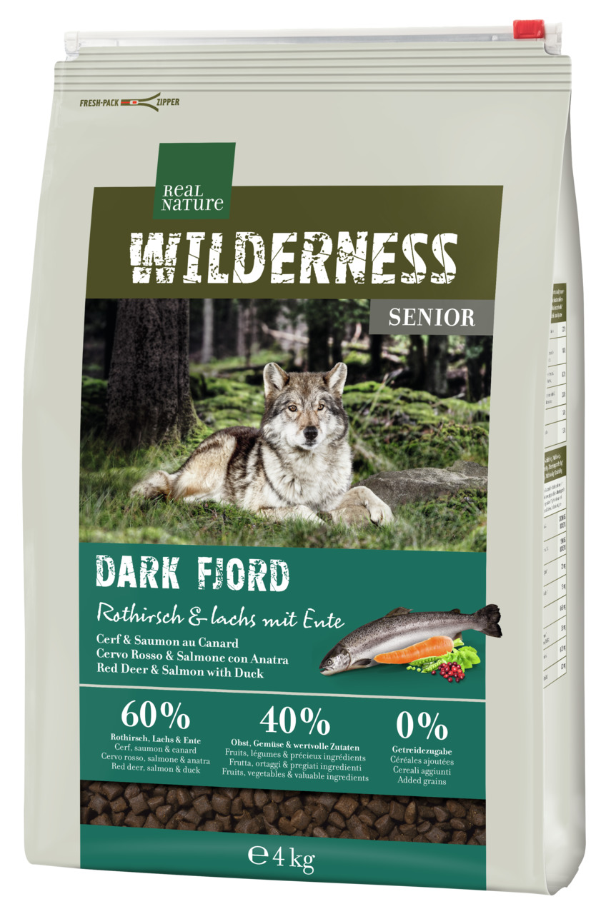 Das Bild zeigt eine Verpackung des Hundefutters „REAL NATURE WILDERNESS Senior Dark Fjord“ mit der Geschmacksrichtung Rothirsch, Lachs und Ente. Zielgruppe sind ältere Hunde. Die Verpackung enthält 4 kg Futter, das zu 60 % aus tierischen Zutaten, 40 % aus