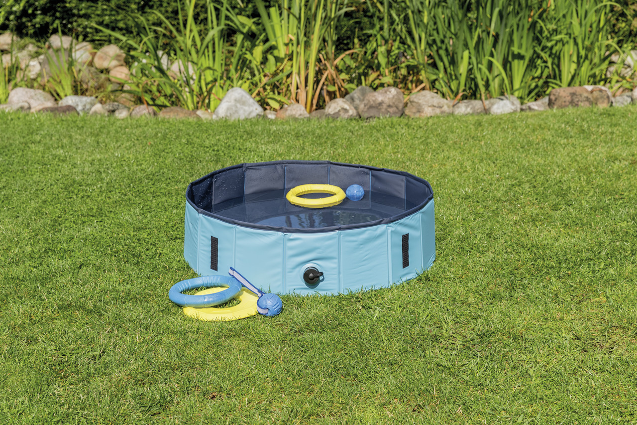 TRIXIE Hundepool, faltbares Schwimmbecken für Hunde, Blau, zur Abkühlung & Spiel im Sommer, inkl. Spielzeug, auf grüner Wiese.