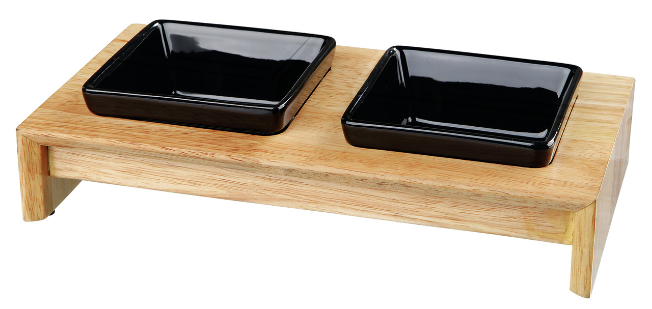 Das Bild zeigt den TRIXIE Napfständer mit zwei schwarzen Keramiknäpfen, die auf einer erhöhten Holzplattform platziert sind. Dieses Produkt ist ideal für Hunde und Katzen, da es eine ergonomische Fütterungshöhe bietet. Die Näpfe sind herausnehmbar und lei