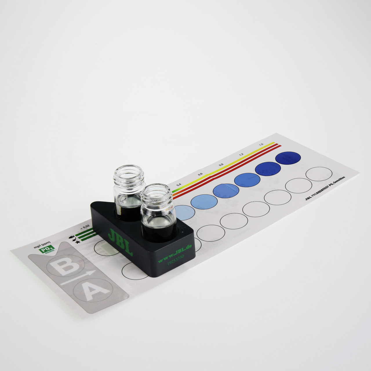 Das Bild zeigt das JBL ProAquaTest PO4 Phosphat-Test-Set, ein Produkt für Aquaristik-Enthusiasten. Es enthält zwei Glasküvetten, eine schwarze Halterung mit JBL-Logo und eine Farbskala zur Bestimmung des Phosphatgehalts im Wasser. Das Set dient der präzis