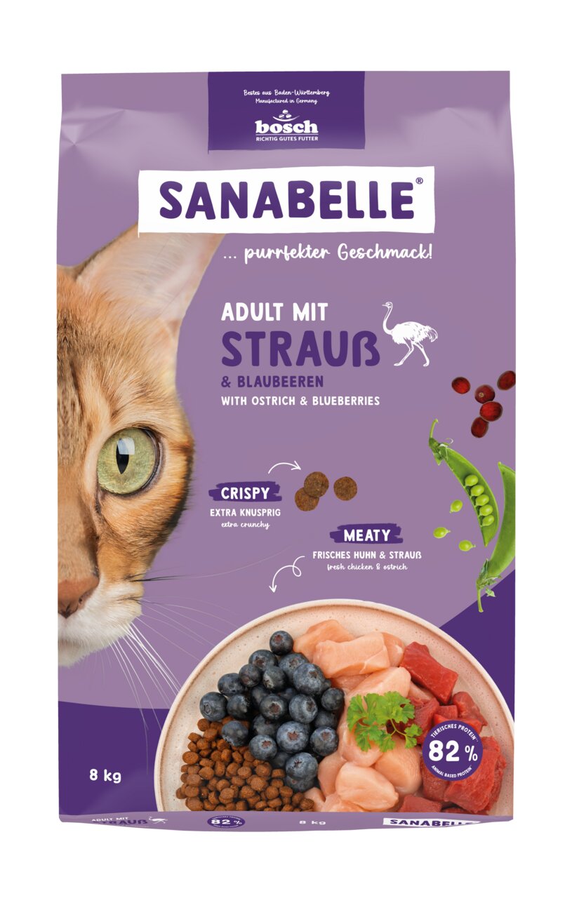 Das Bild zeigt eine lila Verpackung des Katzenfutters „Sanabelle Adult mit Strauß & Blaubeeren“ der Marke Bosch. Es ist für ausgewachsene Katzen geeignet und enthält frisches Huhn, Strauß sowie Blaubeeren. Die Verpackung hebt die knusprige Konsistenz und 