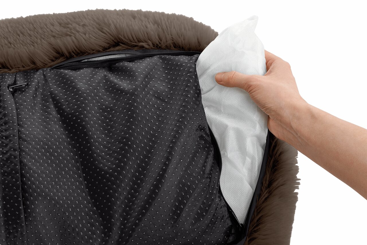 Hand zeigt das Innenleben eines braunen Hundebettes von HUNTER mit herausnehmbarem Kissen. Bezug aus weichem Material.