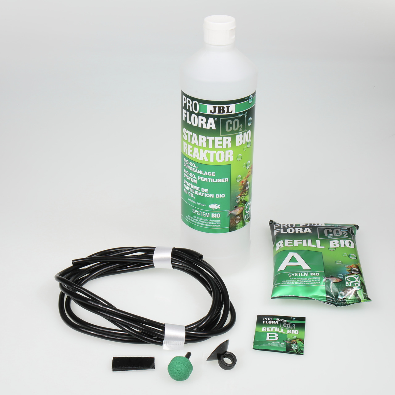 Das Bild zeigt das JBL ProFlora CO2 Starter Bio Reaktor Set, ein Produkt für Aquarienbesitzer. Es enthält eine Flasche mit Bio-CO2-Dünger, Nachfüllpackungen (A und B), einen Schlauch, einen Diffusor und weiteres Zubehör. Das Set ist für Pflanzenliebhaber 
