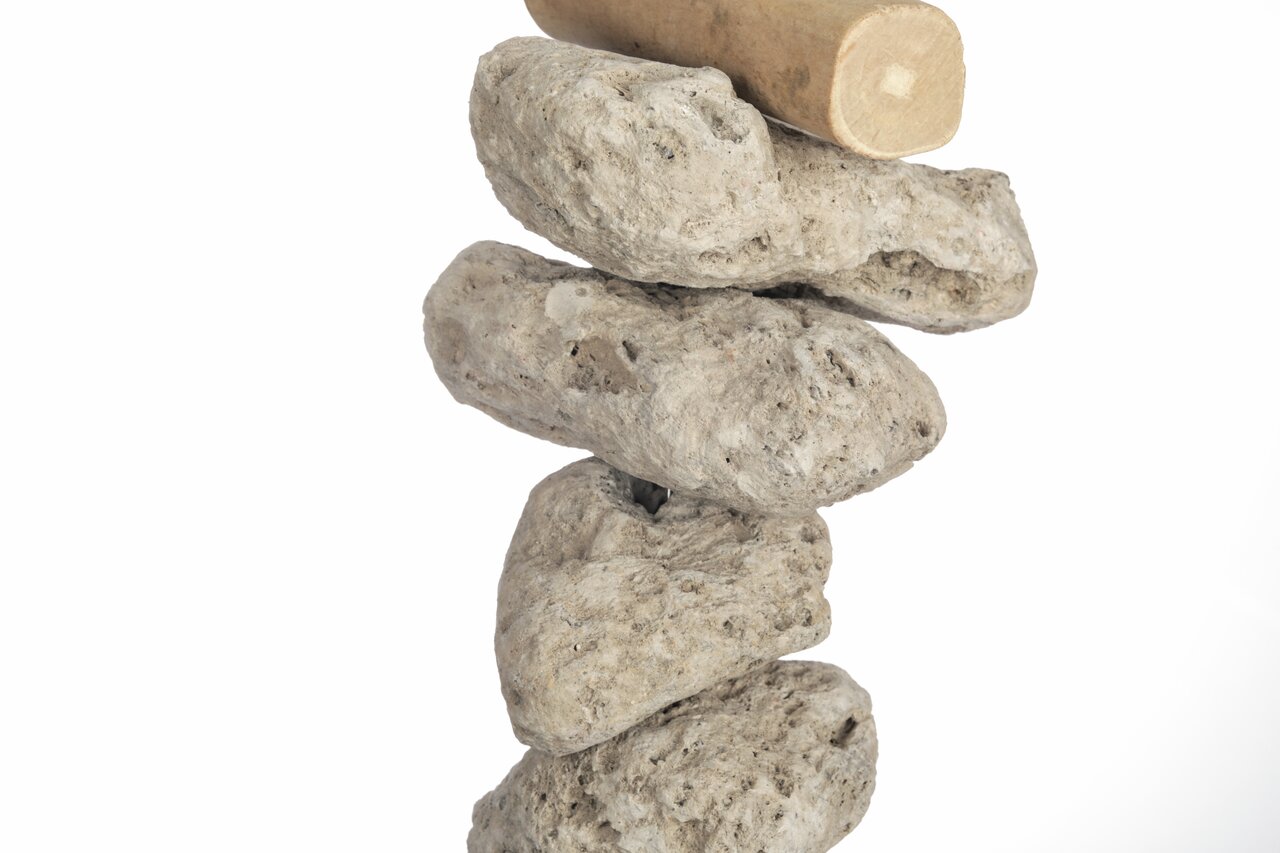 Natürl. Steinstapel mit rauer, beige-grauer Oberfläche u. glattem Holzstück obenauf, vermittelt Balance u. Naturgefühl.