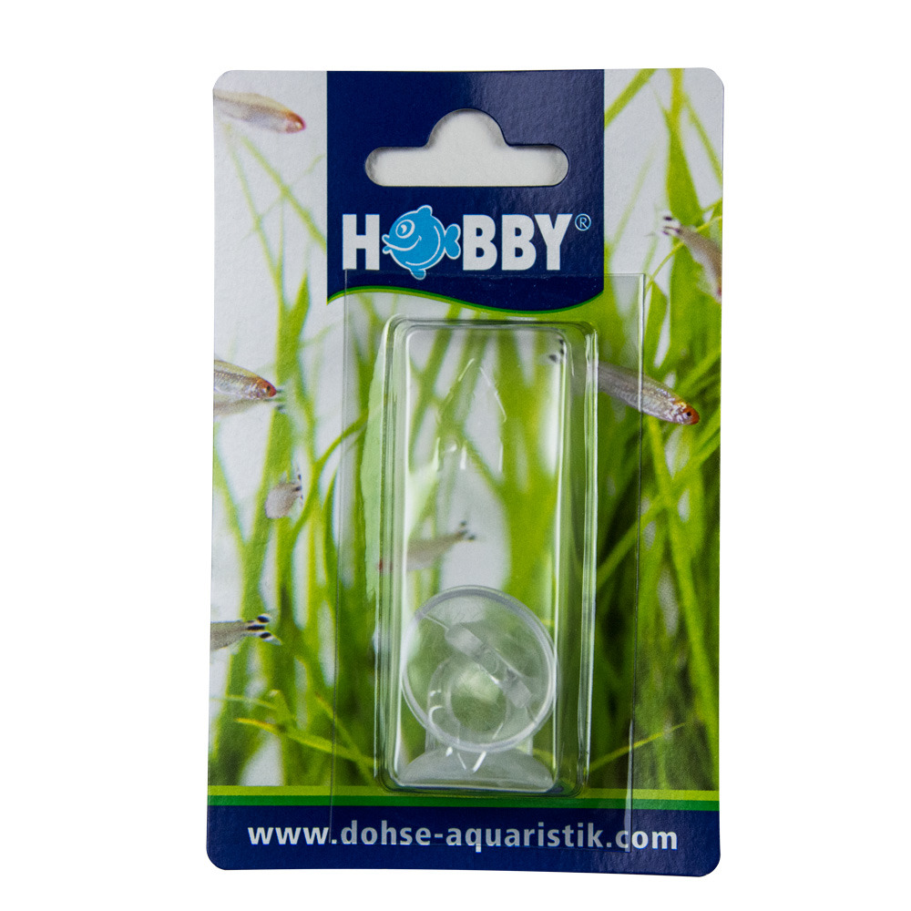 Das Bild zeigt das Produkt „Hobby Saugnapf“ der Marke HOBBY, geeignet für Aquaristik-Enthusiasten. Es handelt sich um einen transparenten Saugnapf, der zur Befestigung von Zubehör im Aquarium dient. Die Verpackung zeigt ein grünes, aquatisches Design mit 