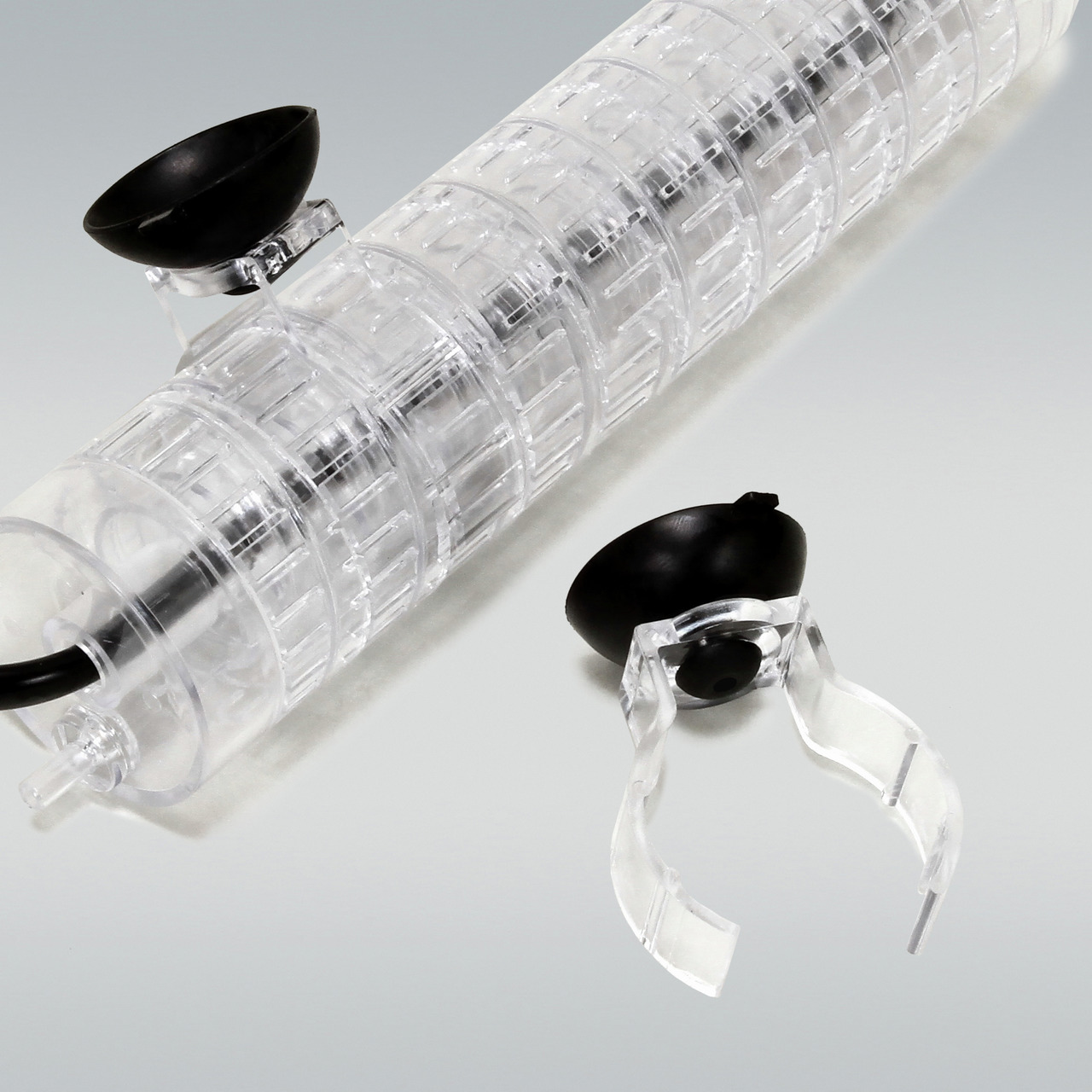 Das Bild zeigt den JBL ProTemp S Heizstabhalter, ein Zubehör für Aquarien. Der Halter besteht aus transparentem Kunststoff und ist mit schwarzen Saugnäpfen ausgestattet, die eine sichere Befestigung im Aquarium ermöglichen. Geeignet für Aquarienliebhaber,