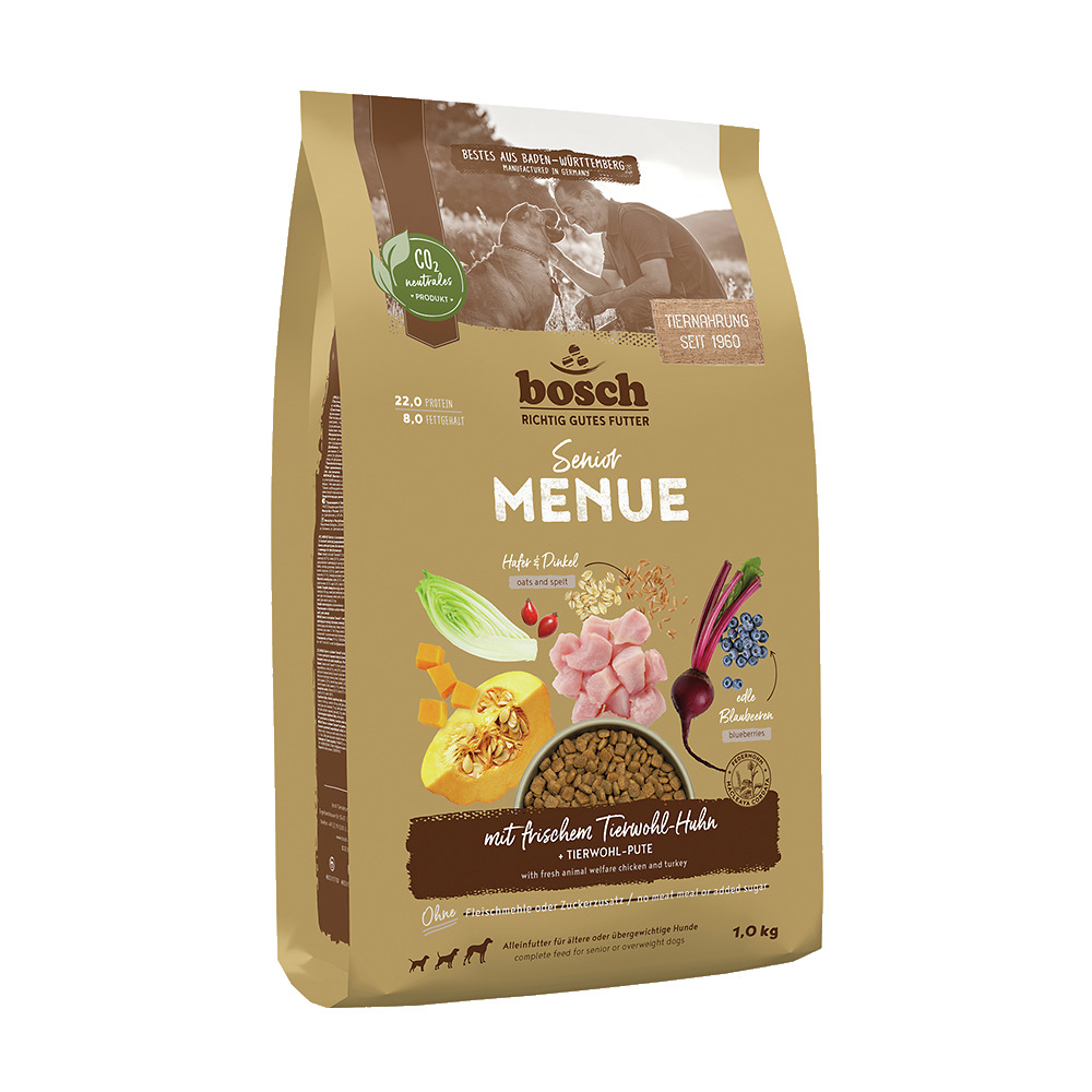 Das Bild zeigt eine 1,0 kg Packung "bosch Senior Menue" Tiernahrung, speziell für ältere oder übergewichtige Hunde. Die Geschmacksrichtung ist frisches Tierwohl-Huhn und Pute, ergänzt mit Hafer, Dinkel und Blaubeeren. Die Verpackung betont CO2-Neutralität