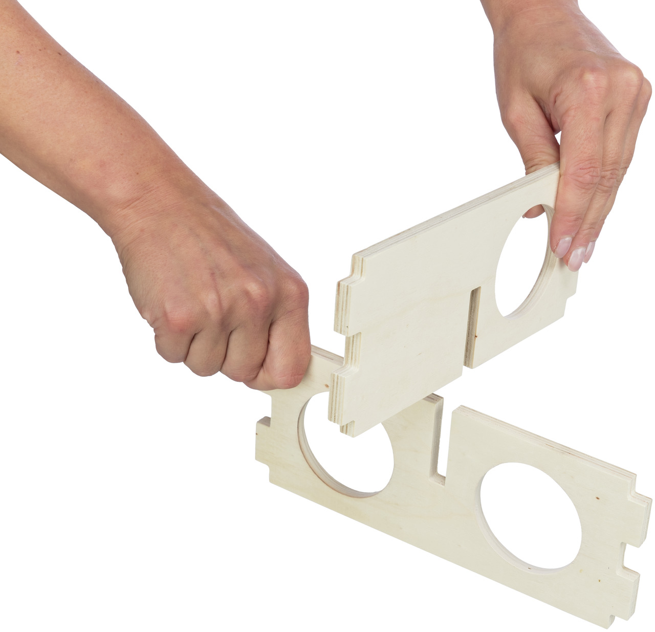 Das Bild zeigt zwei Hände, die Holzteile eines Stecksystems zusammenfügen. Es handelt sich um das Produkt „TRIXIE Kleintier-Spielplatz Stecksystem“ für Kleintiere wie Hamster oder Mäuse. Die Holzteile sind naturbelassen und haben runde Öffnungen. Ideal zu