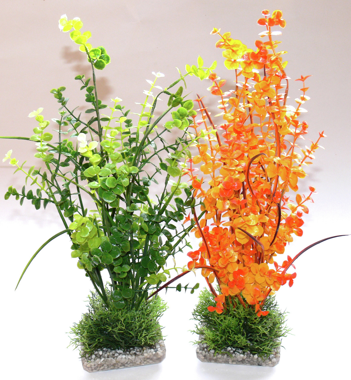 Zwei künstliche Aquarienpflanzen der Marke Sydeco, geeignet für Aquarienliebhaber. Die linke Pflanze zeigt grüne Blätter in verschiedenen Schattierungen, die rechte Pflanze leuchtet in Orange- und Gelbtönen. Beide stehen auf einem Sockel mit Kieselsteinen