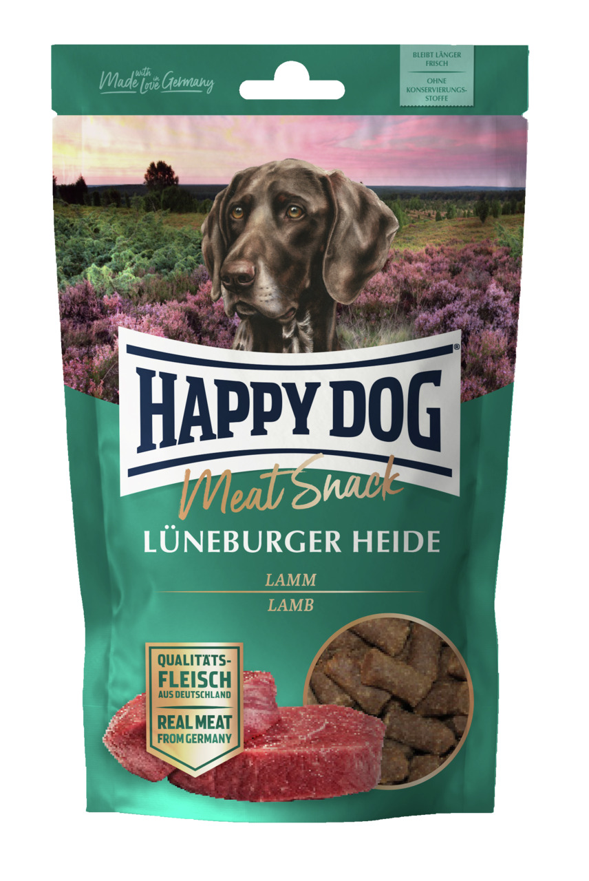 Das Bild zeigt eine grüne Verpackung des Produkts „HAPPY DOG Meat Snack Lüneburger Heide“ der Marke Happy Dog. Es handelt sich um einen Hundesnack mit Lammgeschmack, geeignet für Hunde. Die Verpackung enthält die Aufschrift „Qualitätsfleisch aus Deutschla