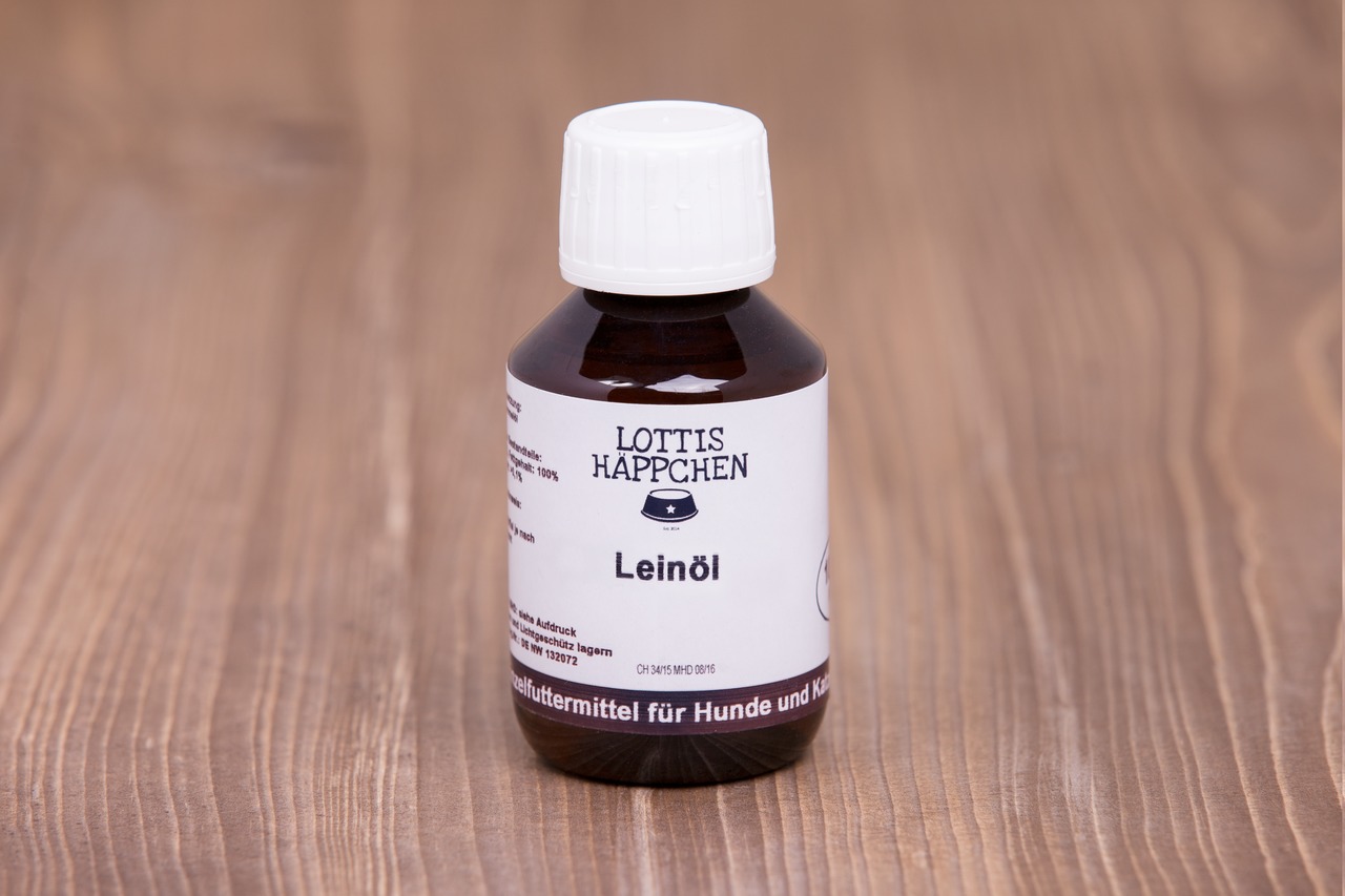 Das Bild zeigt eine braune Glasflasche mit weißem Schraubverschluss, die auf einer Holzoberfläche steht. Es handelt sich um das Produkt „Lottis Häppchen Leinöl“, ein Ergänzungsfuttermittel für Hunde und Katzen. Die Flasche enthält 100 ml reines Leinöl, da