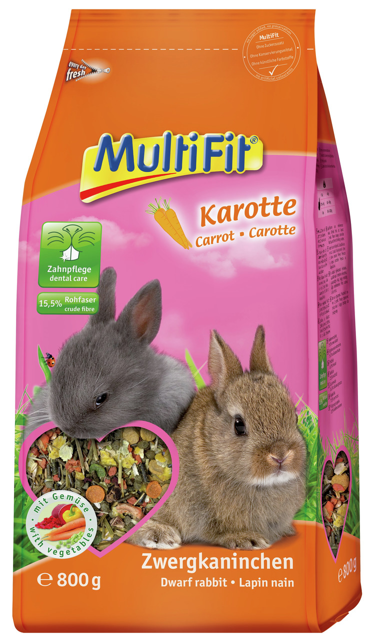 Das Bild zeigt eine orange-pinke Verpackung des Produkts „MultiFit Karotte“ für Zwergkaninchen. Die Marke MultiFit bietet hier ein Futter mit Karottengeschmack an, das speziell für die Zahnpflege entwickelt wurde. Es enthält 15,5 % Rohfaser und ist mit Ge