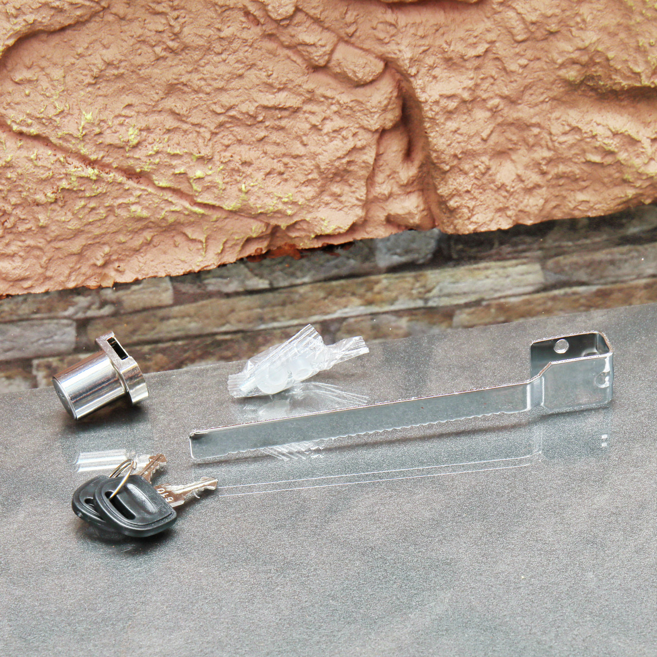 Sicherheitszubehör-Set: verchromter Schlosszylinder, 2 Schlüssel, Metallhalterung, Kunststoffteile zur Montage.