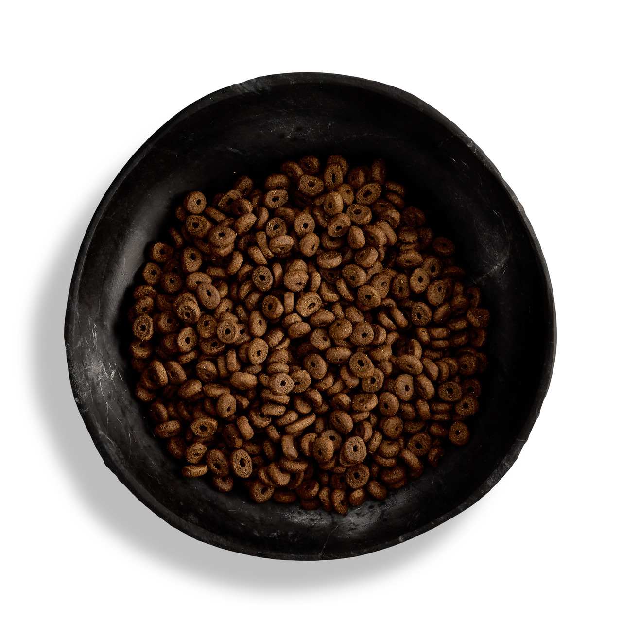 Eine schwarze Schale, gefüllt mit Canagan Hundefutter in kleinen, runden Kroketten. Das Premium-Trockenfutter ist für Hunde aller Rassen geeignet und enthält hochwertige Zutaten. Die Geschmacksrichtung ist nicht angegeben. Die Verpackungsmenge ist auf dem