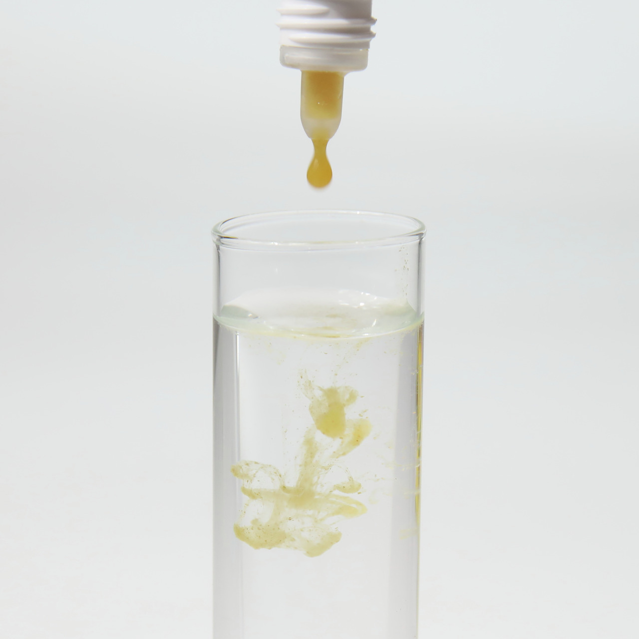 Das Bild zeigt das Produkt JBL Denitrol, ein Wasseraufbereiter für Aquarien. Es richtet sich an Aquarienbesitzer und dient der schnellen biologischen Aktivierung von Filtern. Eine Pipette gibt eine gelbliche Flüssigkeit in ein Glas mit klarem Wasser ab, w