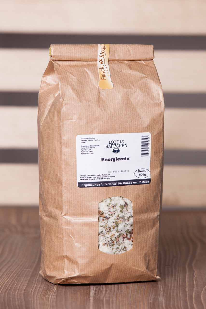 Braune Papiertüte mit Sichtfenster, gefüllt mit einem Ergänzungsfuttermittel für Hunde und Katzen der Marke Lottis Häppchen. Produktname: Energiemix. Zielgruppe: Hunde und Katzen. Enthält natürliche Zutaten wie Gemüse und Kräuter. Nettogewicht: 500 g. Fri