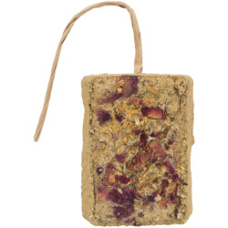 Das Bild zeigt das Produkt „TRIXIE Kräuter-Knabberblock“ für Kleintiere wie Kaninchen und Meerschweinchen. Der rechteckige Block besteht aus gepressten Kräutern und Blüten, darunter Rosenblätter und Kamille, und ist mit einer Schnur zum Aufhängen versehen